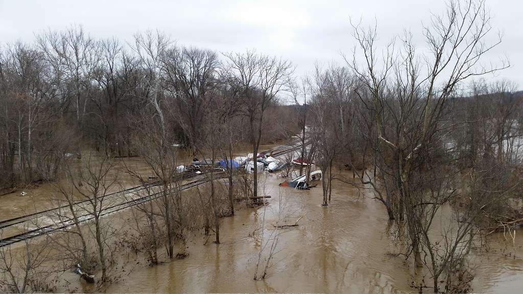 Muddy floodwater spreading over low ground and rail tracks